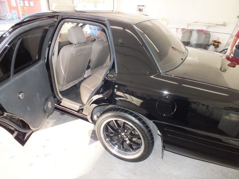 2003 Ford Crown Victoria - Black Crown Victoria rear flank with door open, tan interior and a black machined-lip wheel.