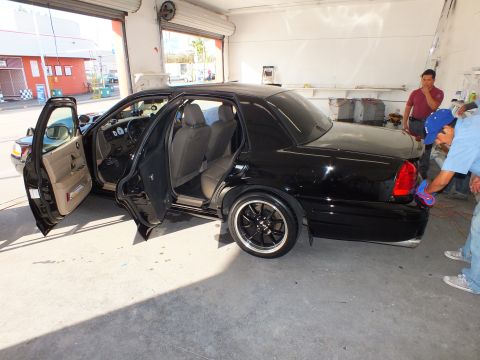 2003 Ford Crown Victoria - Side view of a black Crown Victoria with front door open and dark aftermarket wheels.