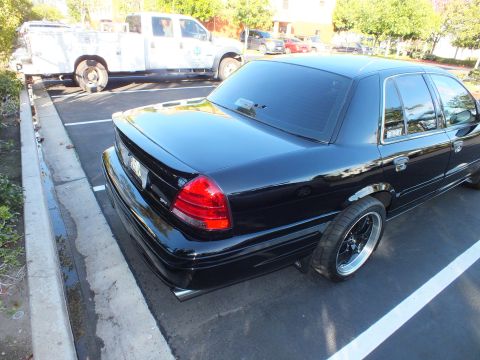 2003 Ford Crown Victoria - Lowered black Crown Victoria parked in a lot with a white utility truck behind it.