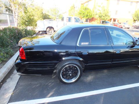 2003 Ford Crown Victoria - Black Crown Victoria parked outdoors showing its full side profile and machined-lip wheels.