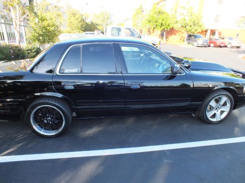 2003 Ford Crown Victoria - Side profile of a lowered black full-size sedan with custom black wheels in a parking lot