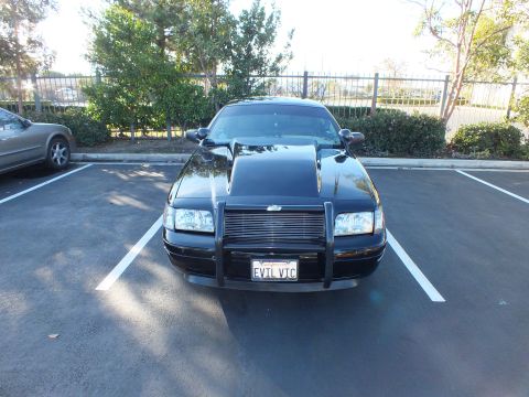 2003 Ford Crown Victoria - Direct front shot of a modified black sedan with grille guard in parking lot