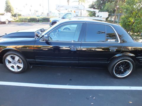 2003 Ford Crown Victoria - Side view of a lowered black sedan with tinted glass in a parking lot