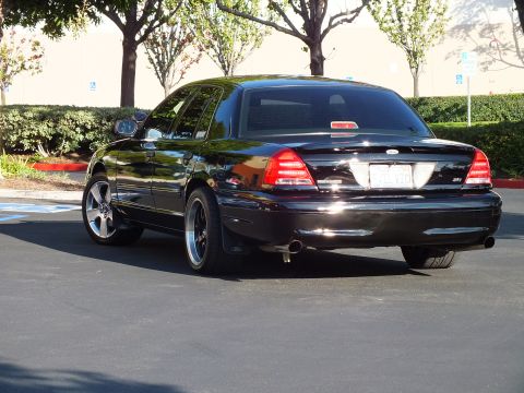 2003 Ford Crown Victoria - Rear view of a black sedan showing taillights, trunk oval badge and twin tailpipes