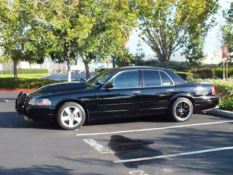 2003 Ford Crown Victoria - Side view of a lowered black sedan with grille guard in daylight parking lot