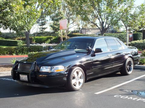 2003 Ford Crown Victoria - Angled front view of a black modified sedan parked under trees