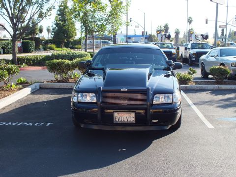 2003 Ford Crown Victoria - Direct front view of a black modified sedan with raised hood scoop