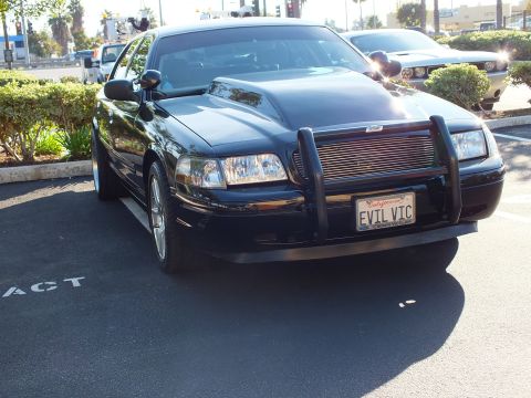 2003 Ford Crown Victoria - Angled front view of a black modified sedan with billet grille in a lot