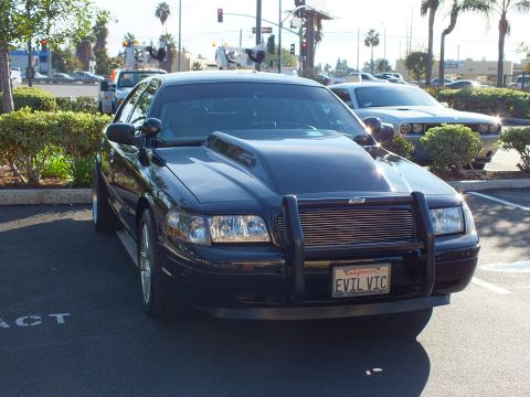 2003 Ford Crown Victoria - Front quarter view of a black modified sedan parked near a busy street