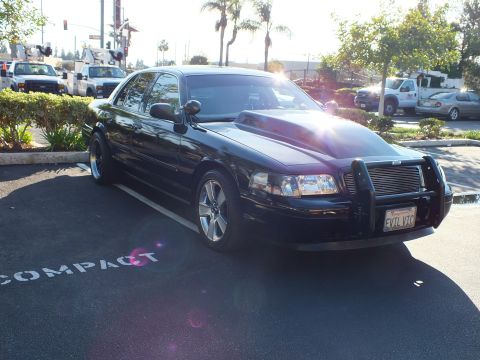 2003 Ford Crown Victoria - Sun glare hits the hood of this blacked-out Mercury sedan; chrome grille guard and front plate read EVIL VIC.