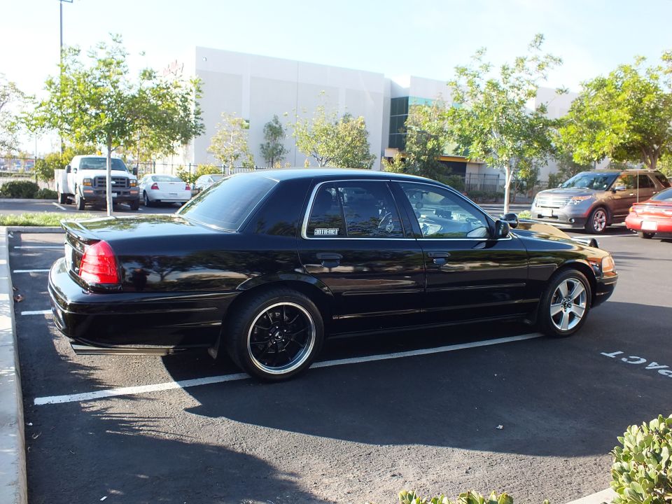 Passenger rear quarter of black Mercury sedan with machined-lip wheels by warehouse