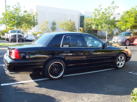 2003 Ford Crown Victoria - Rear-quarter profile of a dropped black full-size sedan, MERCURY decal on the quarter glass.