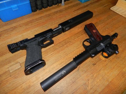 1996 Ford Bronco - Two handguns, one black and one with wood grips, are displayed with suppressors on a wooden table.