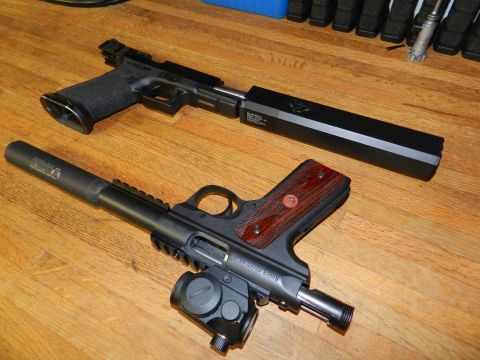 1996 Ford Bronco - Two handguns, one with a textured grip and the other with wood grips and a red dot sight, are displayed on a wooden table.