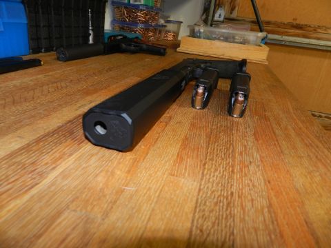 1996 Ford Bronco - A pistol with a suppressor and loaded magazines are displayed on a wooden table, with ammunition boxes in the background.