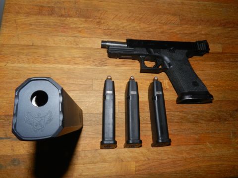 1996 Ford Bronco - A black pistol with a suppressor and three loaded magazines are laid out on a wooden table. The website "SUPERMOTORS.NET" is visible in the…
