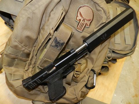 1996 Ford Bronco - A handgun with a suppressor rests on a tactical backpack adorned with patches.