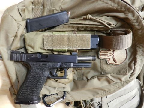 1996 Ford Bronco - A handgun and its magazine are laid out on a tan tactical backpack, complete with a Punisher skull patch.