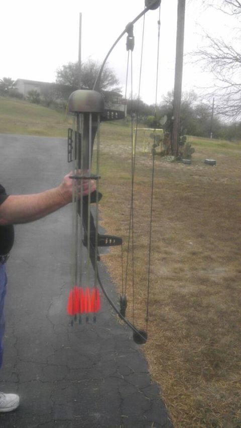 1989 Ford Bronco - A compound bow with a quiver holding red-fletched arrows is held by a person's arm.