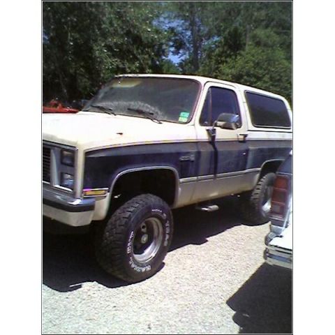1989 Ford Bronco - This two-tone SUV features a lifted suspension and aggressive off-road tires, parked outdoors.