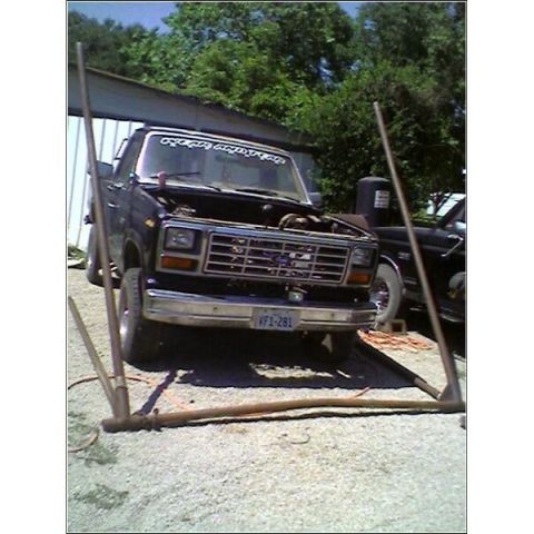 1989 Ford Bronco - A black Ford truck from the early 1980s is parked outside with its hood open.