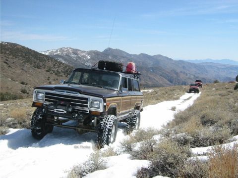 1989 Ford Bronco - A convoy of Jeeps navigates a snow-covered trail in a mountainous landscape.