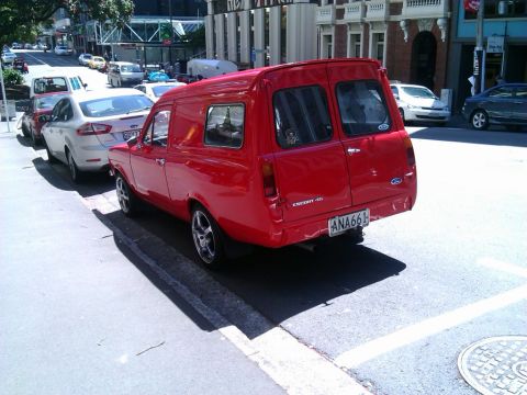 1969 Lincoln Continental - A red Ford Escort van is parked on a city street next to other vehicles.