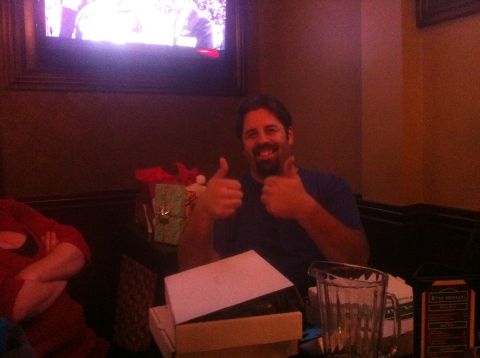 1989 Ford Bronco - A man smiles and gives a double thumbs-up gesture while seated at a table with gifts and a pitcher.