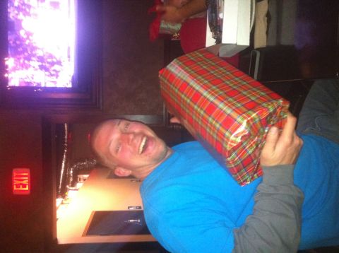 1989 Ford Bronco - A man joyfully holds a large, plaid-wrapped gift in front of his face during a festive gathering.