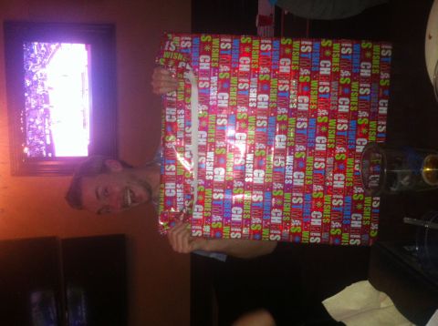 1989 Ford Bronco - A man smiles while holding a large gift wrapped in festive paper with 'Christmas Wishes' repeated throughout.