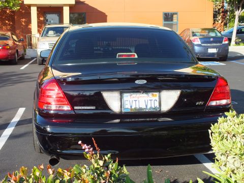 2003 Ford Crown Victoria - Rear of a black Crown Victoria showing California plate reading EVIL VIC and dual exhaust tips.