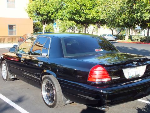 2003 Ford Crown Victoria - Black Crown Victoria sedan parked angled, dark window tint and polished-lip wheels.