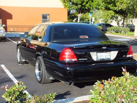 2003 Ford Crown Victoria - Black Crown Victoria parked rear-in against an orange building, plate reads EVIL VTC.