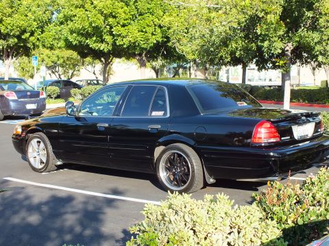 2003 Ford Crown Victoria - Black Crown Victoria sedan parked angled with chrome-lip wheels, rear quarter in view.