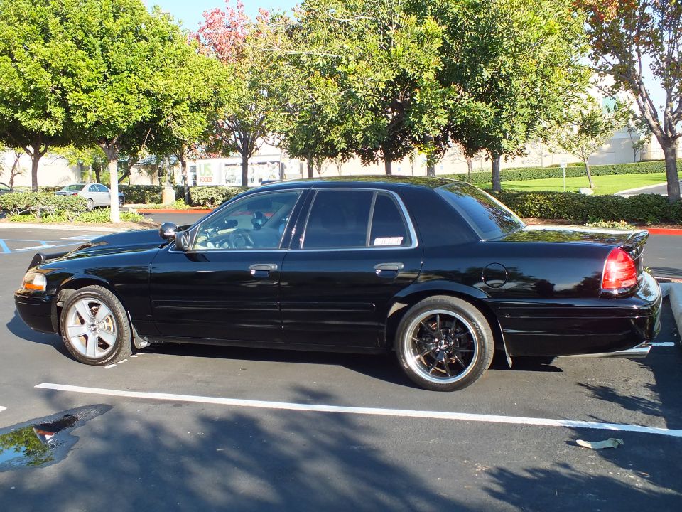 Black Ford Crown Victoria driver-side profile with chrome-lip rear wheel