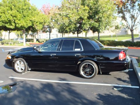 2003 Ford Crown Victoria - Black Crown Victoria sedan shot from the left rear in a striped parking space.