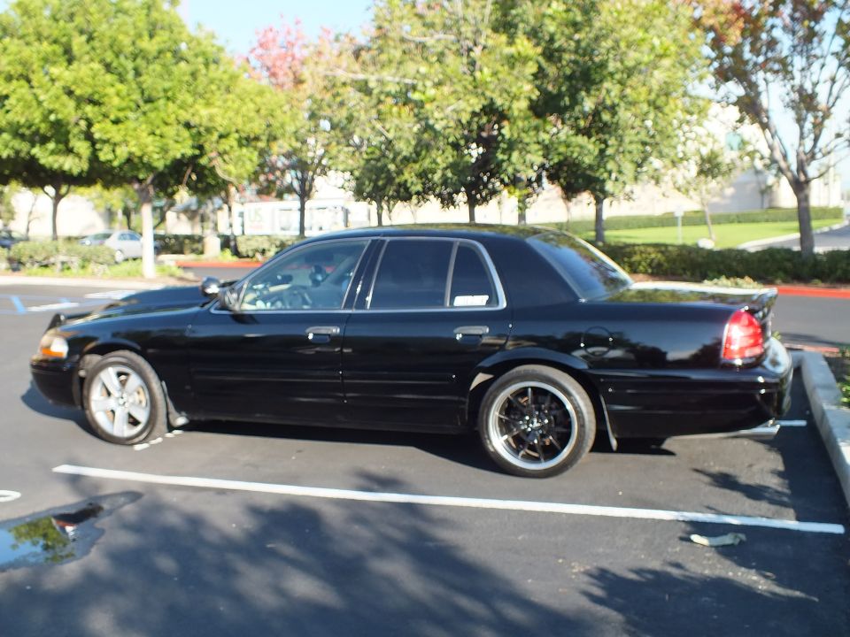 Black Ford Crown Victoria driver-side rear three-quarter with black wheels
