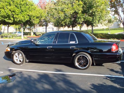 2003 Ford Crown Victoria - Lowered black Crown Victoria parked left-side-on near trimmed hedges.