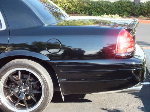 2003 Ford Crown Victoria - Close-up of a black Crown Victoria rear quarter panel, taillight and black wheel in frame.