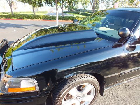 2003 Ford Crown Victoria - Front quarter of a black sedan showing a domed hood, body-color mirror and amber turn signal.