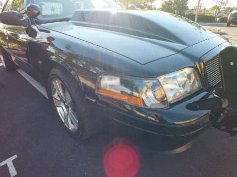 2003 Ford Crown Victoria - Front corner of a black sedan with a chrome vertical-bar grille and amber turn lens.