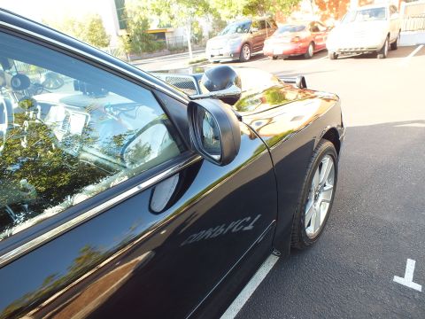 2003 Ford Crown Victoria - Driver door, mirror and front wheel of a glossy black sedan in a parking lot.