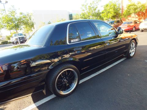 2003 Ford Crown Victoria - Full side view of a lowered black sedan, polished-lip wheels and tinted glass.