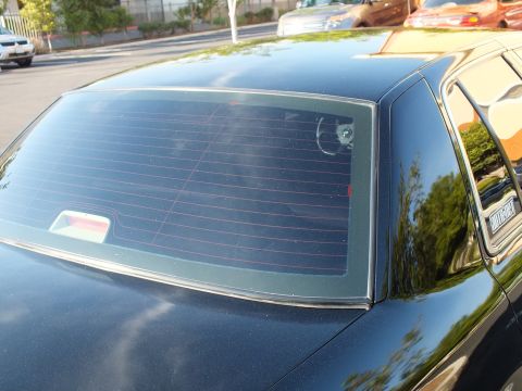 2003 Ford Crown Victoria - Close view of a black sedan rear glass showing defroster grid and brake lamp.