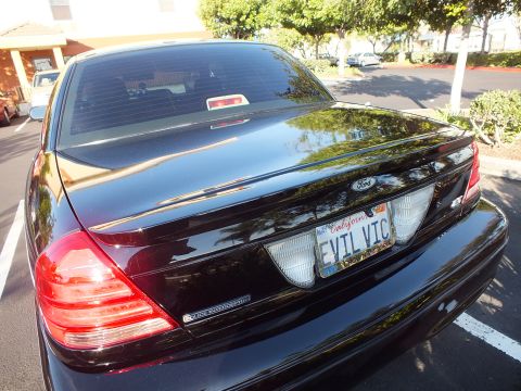 2003 Ford Crown Victoria - Rear of a black Ford sedan badged Police Interceptor with a California EVIL VIC plate.