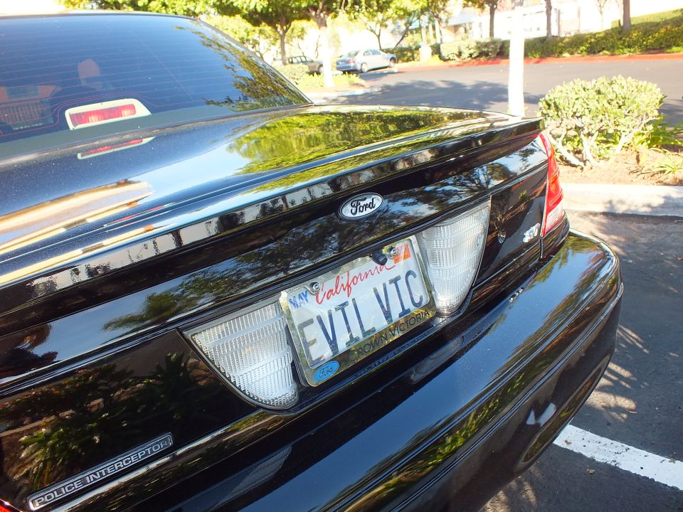 Rear trunk of black Ford Crown Victoria with EVIL VIC California plate and Police Interceptor badge