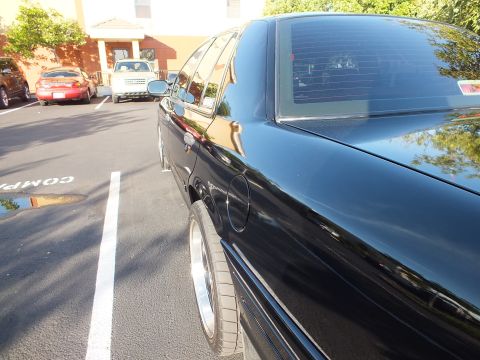 2003 Ford Crown Victoria - Low-angle side shot of a black Ford sedan in a parking lot, polished black paint with chrome trim.