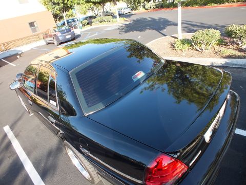 2003 Ford Crown Victoria - High-angle shot looking down on the glossy black roof and rear glass of a Ford sedan.