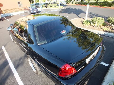 2003 Ford Crown Victoria - Looking down on a black Ford sedan's rear corner, dark tinted glass and red taillight visible.