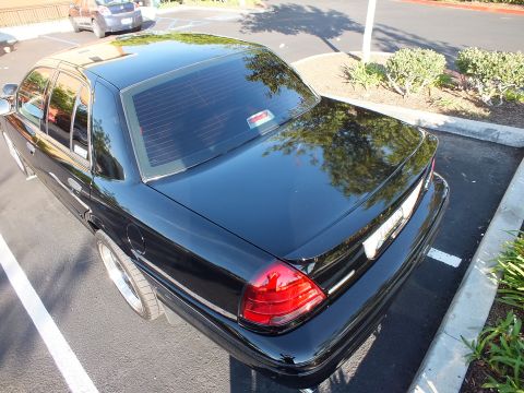 2003 Ford Crown Victoria - Overhead rear view of a black Ford sedan, glossy decklid and single red taillight in frame.